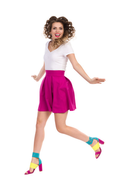 跳跃快乐的年轻女子在彩色高跟鞋和洋红迷你裙图片下载