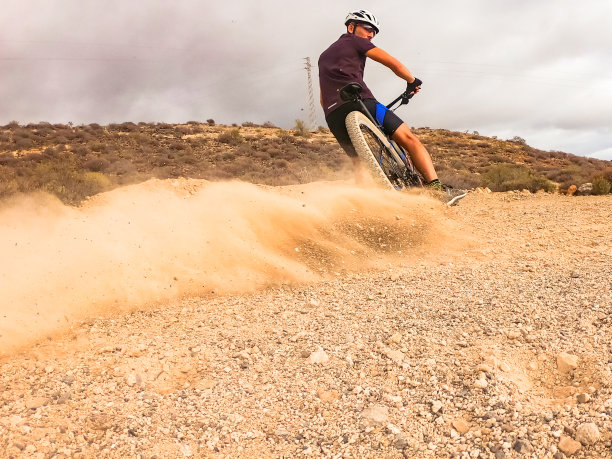 运动员户外自行车训练-下坡运动员在山路上滑行。极限运动概念-形象图片下载