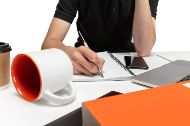 特写镜头。年轻人，学生写作，在白色工作室背景的记事本上做笔记。图片下载