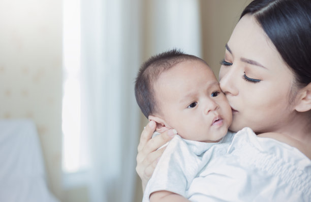 特写照片，美丽的年轻亚洲母亲亲吻她的新生儿在医院的床上。医疗保健医疗家庭爱的生活方式母乳喂养幼儿园motherâ’s day together概念图片下载