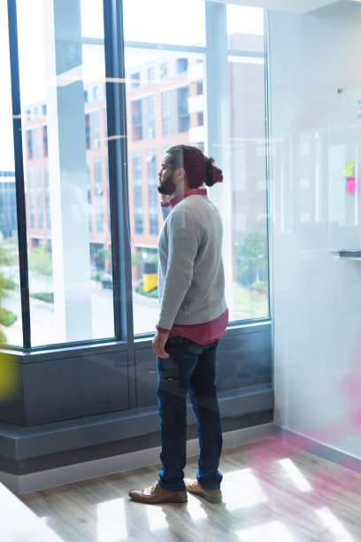 混血男创意工作者在窗边用手机交谈图片下载