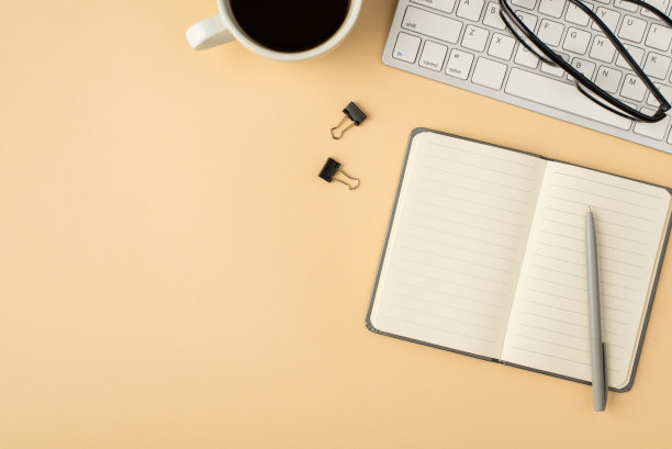 在键盘上打开灰色提醒笔和活页夹上孤立的米色背景与copyspace杯子眼镜的顶部视图照片图片下载