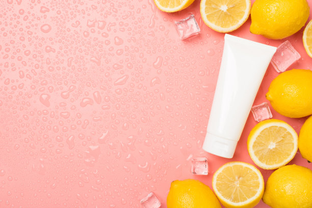 顶部视图照片的白色奶油管切割和整个柠檬冰块在右边的水滴在孤立的淡粉色背景与copyspace在左边图片下载