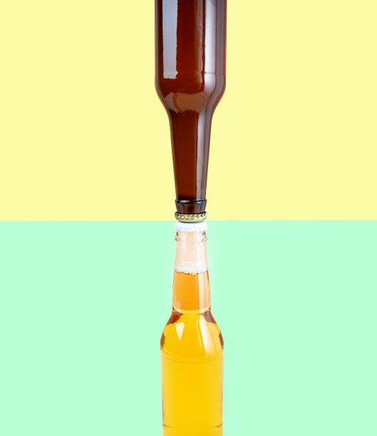 一瓶精酿淡啤酒和黑啤酒，双色黄绿背景。国际啤酒日或十月啤酒节的概念。照片上简约的色彩。前视图。副本的空间。垂直图片下载