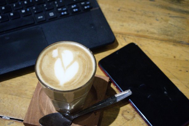 卡布奇诺咖啡和桌上的笔记本电脑图片下载