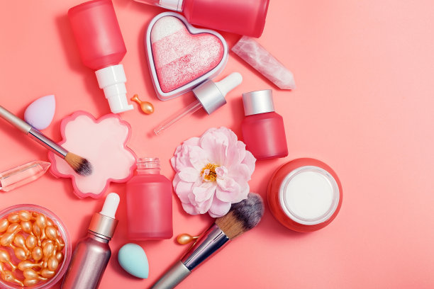 化妆品，俯视图。粉色的瓶子和管子，有分配器，美容搅拌机，腮红，小瓶，刷子，霜，精华液图片下载