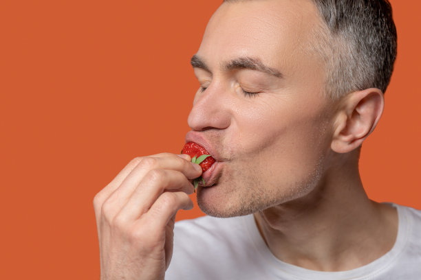 一个男人吃新鲜草莓的特写镜头图片下载