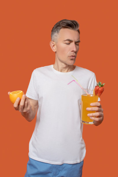 手里拿着鸡尾酒和柑橘的严肃男人图片下载