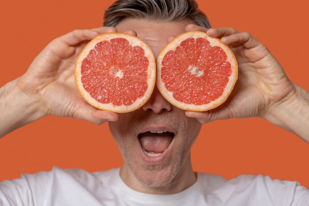 特写男子的脸和半个葡萄柚图片下载