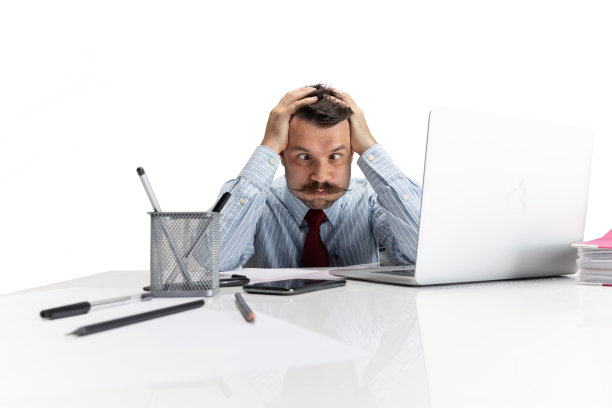 累的工作。一个年轻的白人男子，白领坐在他的工作场所的白色背景。图片下载