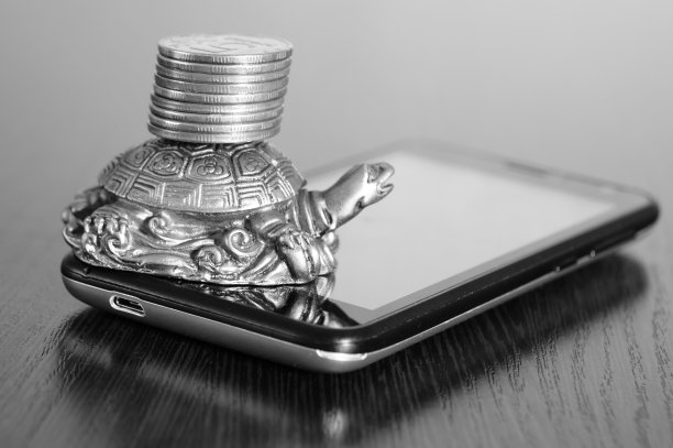 你的智能手机上有硬币的金属乌龟。图片下载