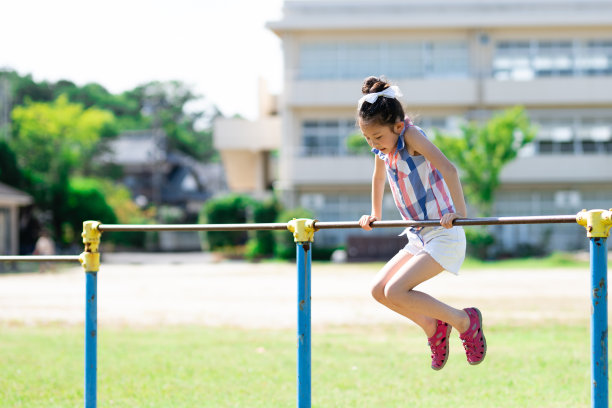 女孩在校园里玩单杠图片下载