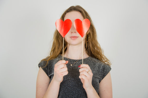 女孩拿着红纸心形靠近她的眼睛图片下载