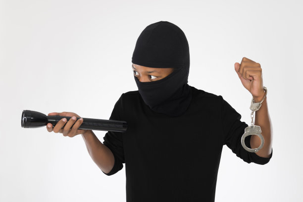 一个拿着手电筒的小偷被隔离在白底上。图片下载