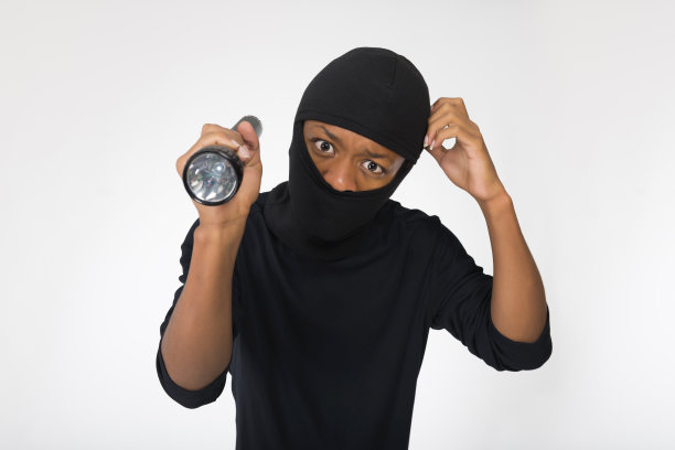 一个拿着手电筒的小偷被隔离在白底上。图片下载