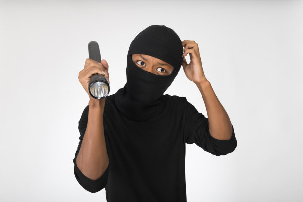 一个拿着手电筒的小偷被隔离在白底上。图片下载