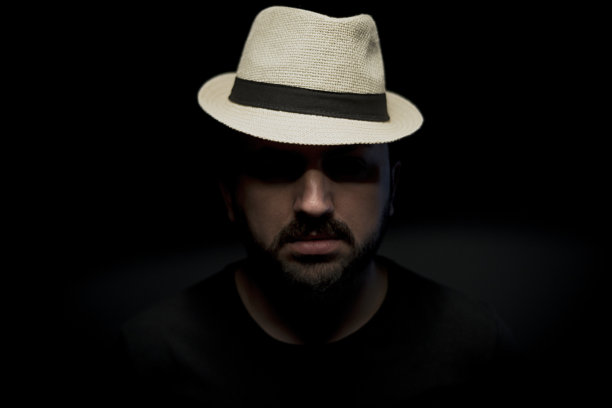 一名男子在黑色背景下戴着帽子低调的照片。图片下载