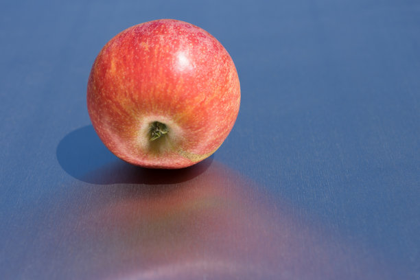 新鲜的红苹果，干净的蓝色背景在阳光下图片下载