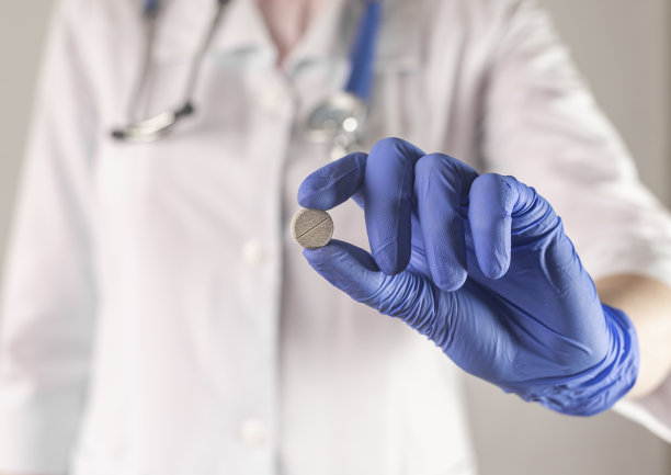 医生手里拿着灰色的圆指药近距离接触。戴着装有药片的蓝色手套图片下载