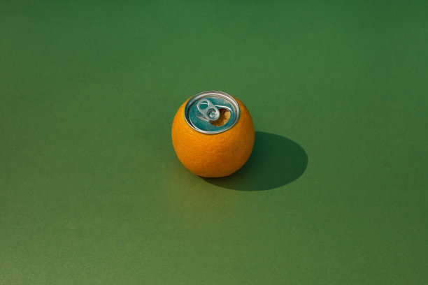 打开绿色背景上的橙色罐头。新鲜的概念。图片下载