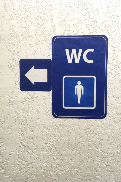 灰泥墙上公共男厕所signб的蓝板上有箭头、指针。厕所的迹象。厕所.WC概念。垂直拍摄。特写镜头。图片下载