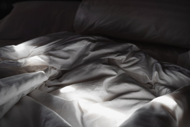 特写白色的毯子和枕头，在床上，与阴影和阴影在早晨图片下载