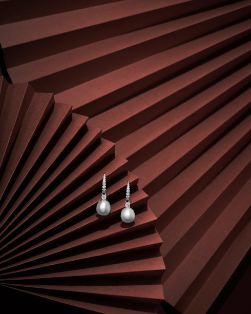 豪华白金色银耳环在棕色纸表面与阴影图片下载