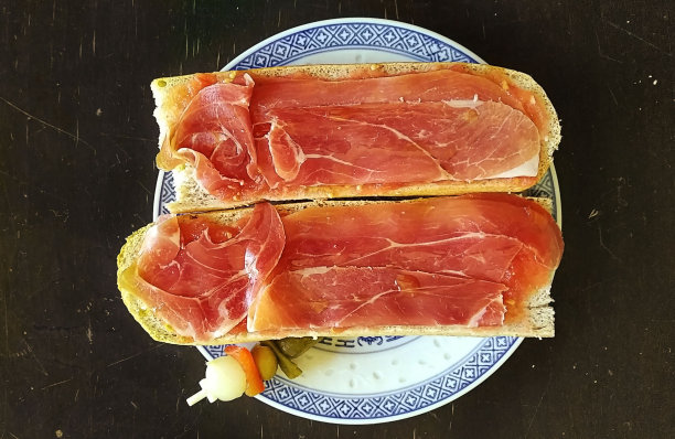 早餐有面包、火腿和西红柿，上面是一张烤面包的图片，背景是一张木桌图片下载