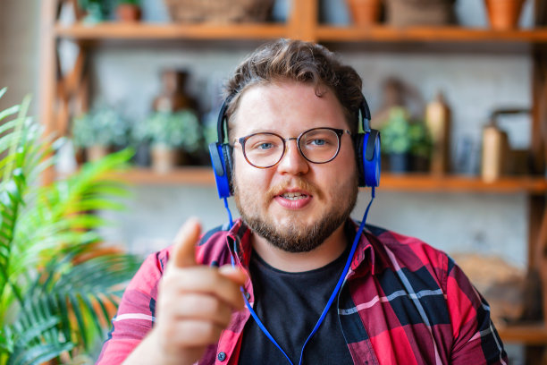 一名年轻男子戴着蓝色耳机或耳机进行在线视频通话的照片图片下载