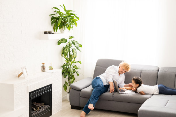 成熟的祖母在家帮孩子做作业。满意的老奶奶在客厅里帮助她的孙女学习。小女孩和坐在她旁边的高级老师在笔记本上写字图片下载