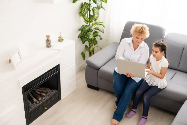 成熟的祖母在家帮孩子做作业。满意的老奶奶在客厅里帮助她的孙女学习。小女孩和坐在她旁边的高级老师在笔记本上写字图片下载