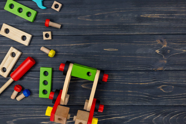 为孩子们设计的彩色木制建筑套件。一套工具放在深色木桌上。为学龄前或日托儿童提供的游戏和工具。自然、环保的玩具。图片下载