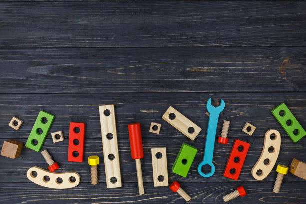 为孩子们设计的彩色木制建筑套件。一套工具放在深色木桌上。为学龄前或日托儿童提供的游戏和工具。自然、环保的玩具。图片下载