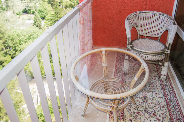 阳台上有一个舒适的座位区，有藤条柳条椅，透明的玻璃桌子和地毯，一个家庭娱乐的概念图片下载