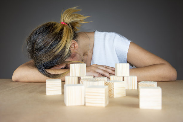 不成功而疲惫的女人用手捂住脸，把头放在桌子上图片下载