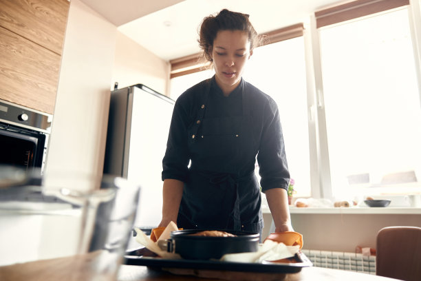 年轻的职业女厨师正在她的轻现代厨房里准备美味的蛋糕图片下载