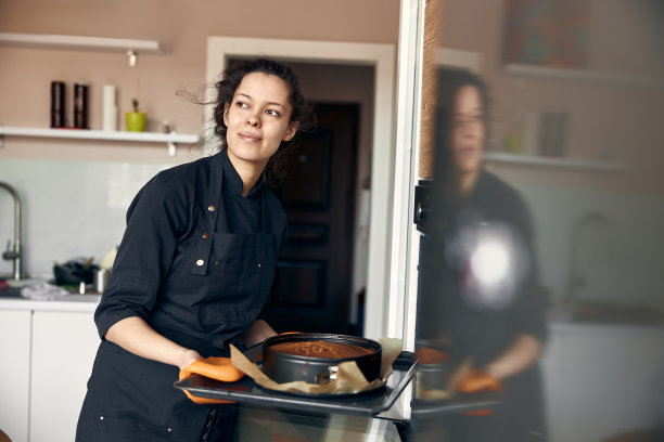 年轻的职业女厨师正在她的轻现代厨房里准备美味的蛋糕图片下载