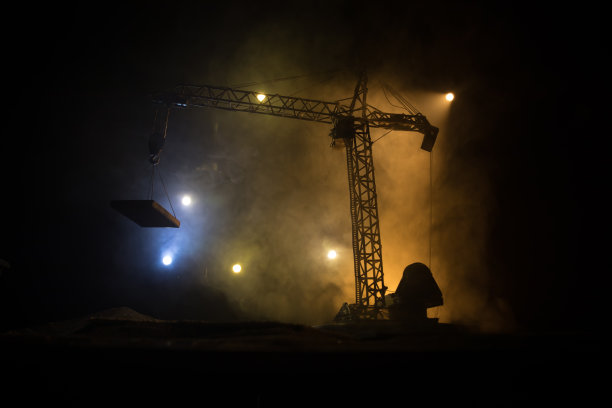 工业背景与建筑起重机剪影在令人惊叹的夜空与雾和背光。塔吊在雾蒙蒙的夜空下。图片下载