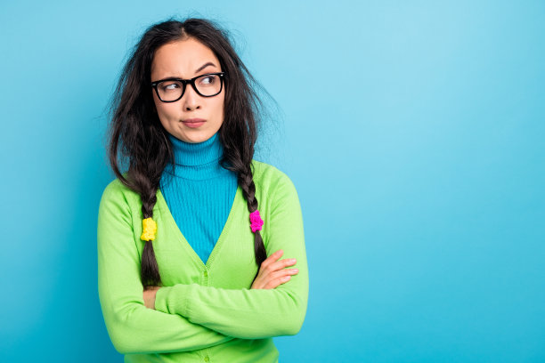 照片中好奇迷人的年轻女子望空扬起眉毛合拢双手孤立在蓝色背景上图片下载