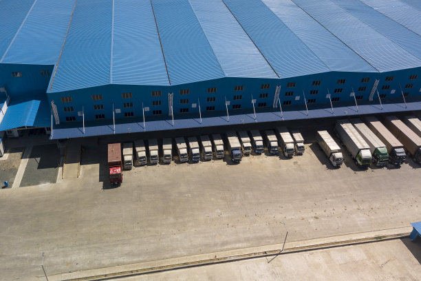 空中的许多半卡车和卡车停在一个大型蓝色仓库或物流中心或卸货。物流和交付概念。图片下载