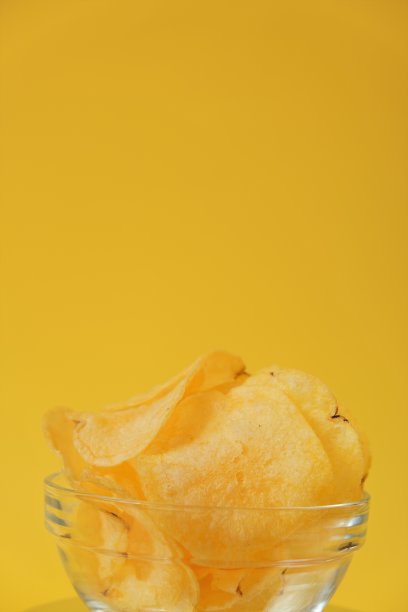 薯片、薯片、快餐和零食。亮黄色背景上的芯片特写。开胃的脆薯片。图片下载