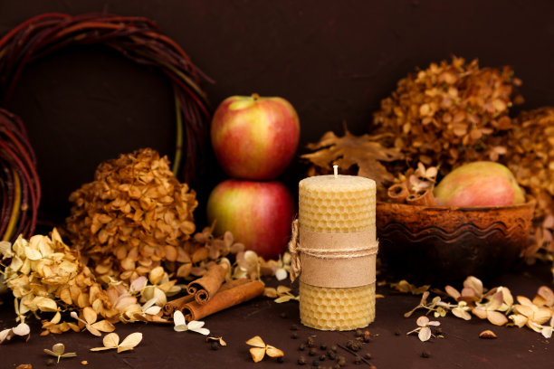 手工制作的蜂蜡蜡烛，棕色背景上的肉桂、苹果和干绣球花。蜂蜜芳香的室内和传统。模型,前视图。图片下载