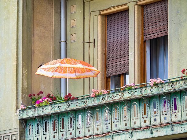 罗马尼亚蒂米什瓦拉的一个用花和遮阳伞装饰的阳台的古老建筑细节图片下载
