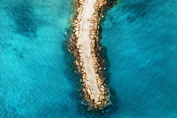 从上往下俯瞰亮蓝色海面上的石制防波堤图片下载