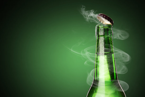 一瓶冰镇饮料滴。打开啤酒盖与气体输出。图片下载