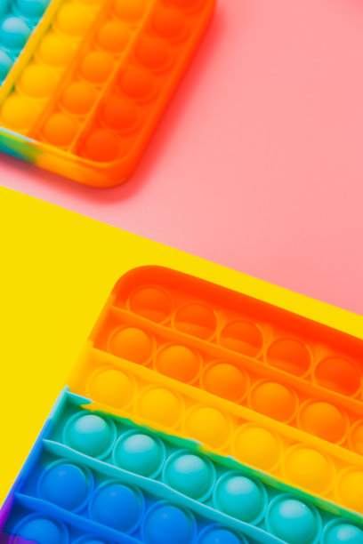 两部分彩色彩虹抗压力弹出它玩具的黄色和粉红色的背景。创造性的概念。平铺，俯视图。图片下载