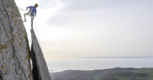 登山运动员准备在日出时用绳索下山图片下载