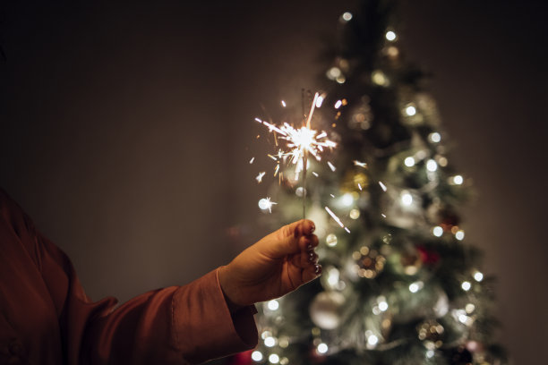不知名的女人拿着新年洒水车，背景是一棵装饰过的圣诞树图片下载