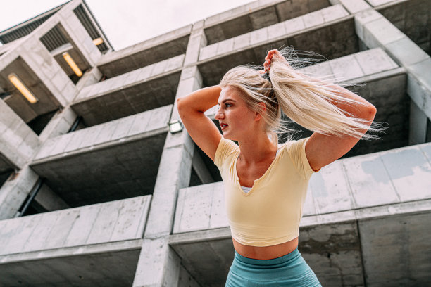 史诗般的低角度英雄照片，一个年轻，积极，健康的金发白种人女人站着，固定她的马尾辫和恢复后的户外跑步图片下载