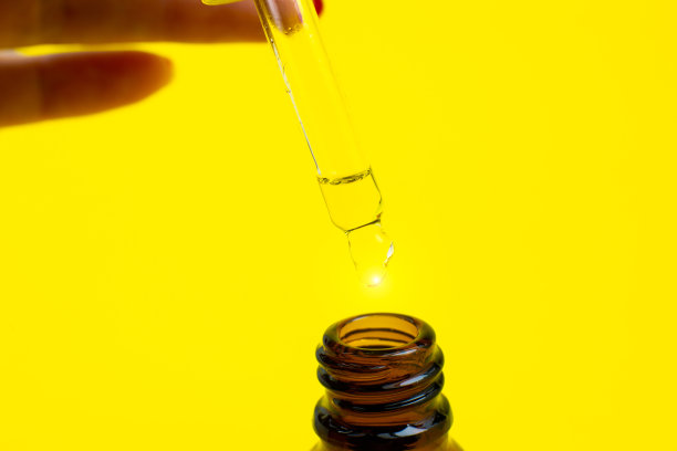 一瓶带吸管的化妆油，黄色背景。关闭液体滴滴。美容、医药、保健理念。宏观照片。自然,生态化妆品。图片下载